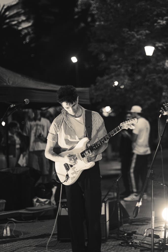 Naza playing an electric guitar on an outdoor stage at night