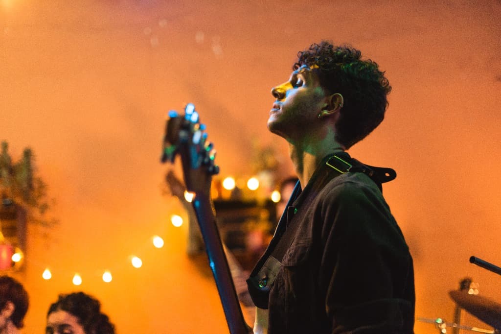 Naza on stage with a bass under warm orange lights
